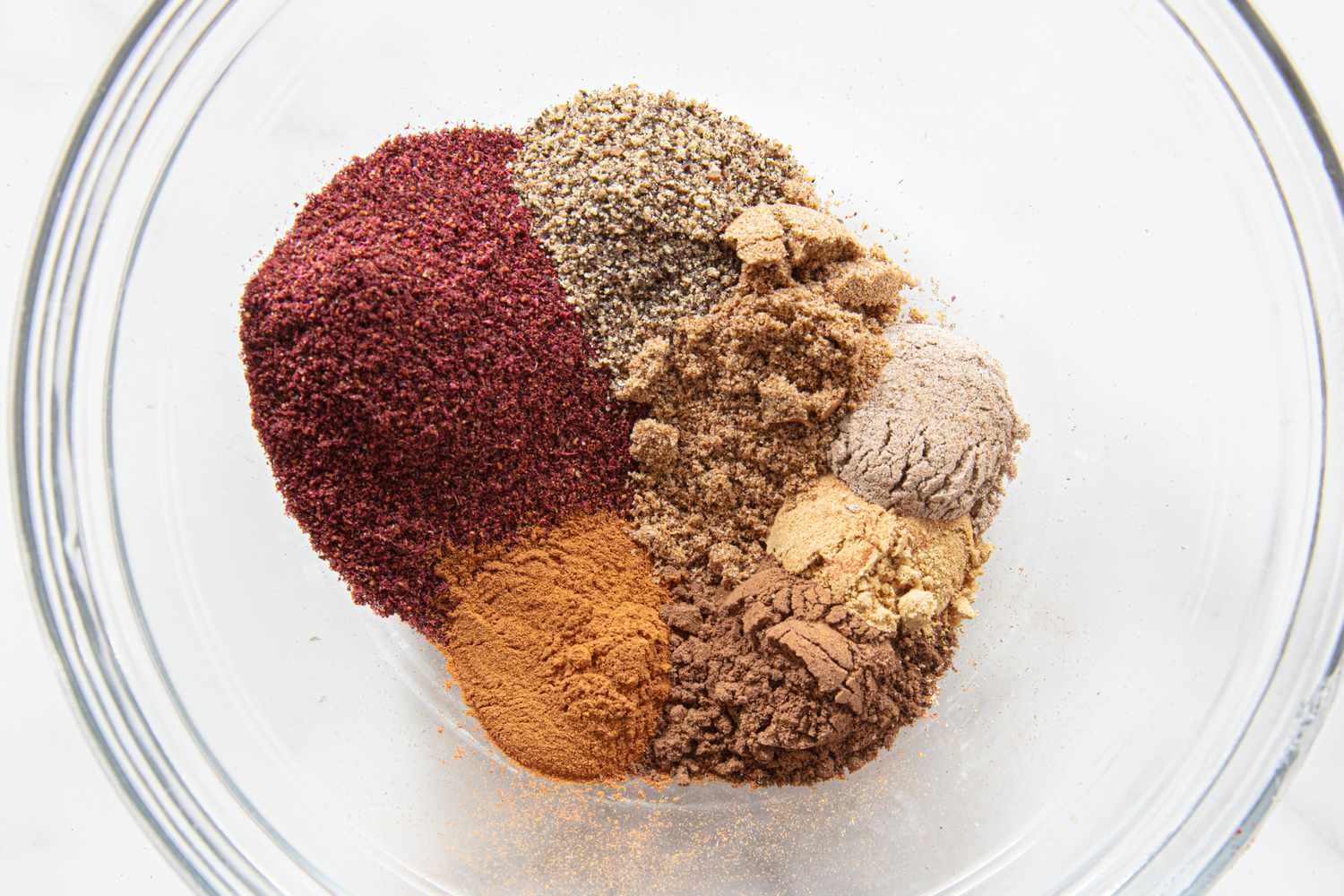 A bowl containing separate piles of different ground spices