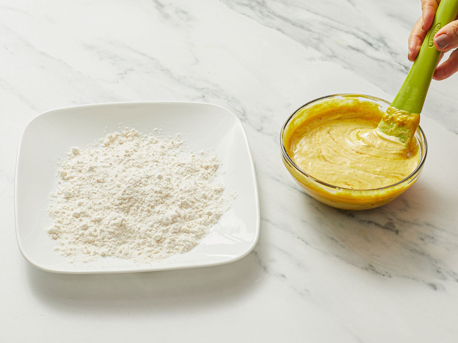 A hand mixing honey mustard next to a plate of flour