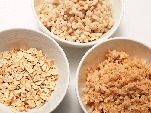 Three white bowls holding different grains.