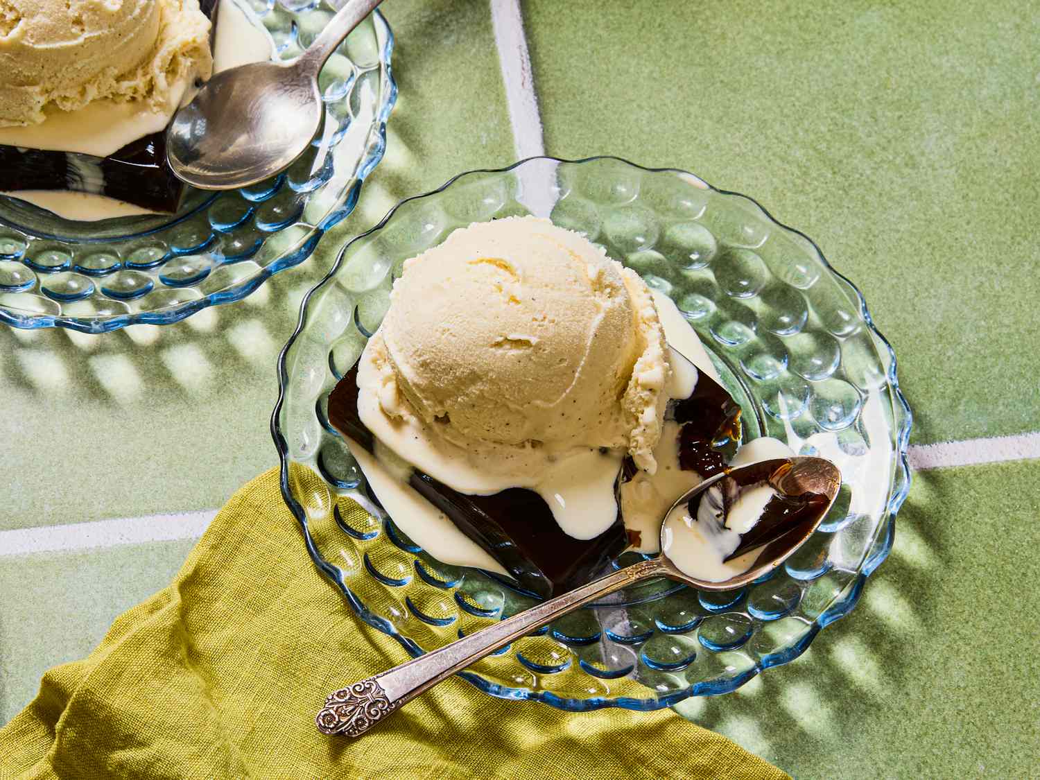 An arrangement of dessert consisting of ice cream and coffee gelatin on a glass plate with a spoon on the side