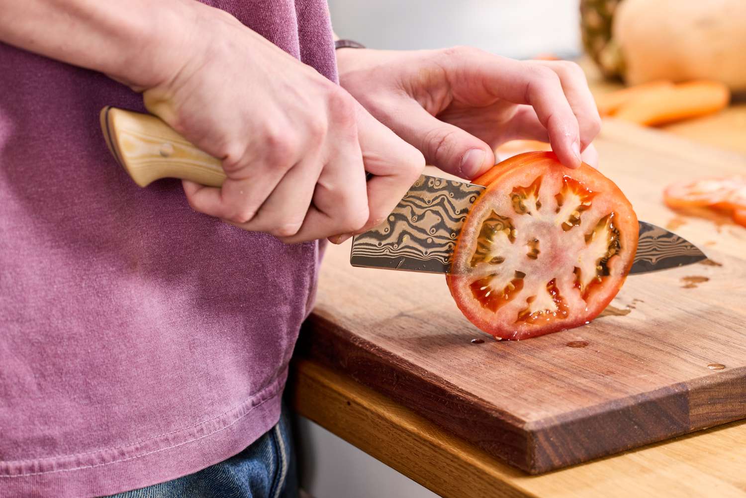 A person slicing a tomato with the Zwilling Kanren 8 Inch Chef's Knife
