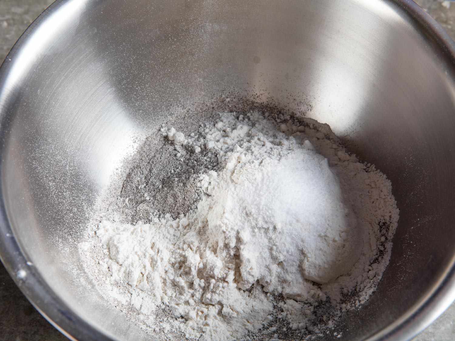 Overhead shot of a mixing bowl containing the dry ingredients of the crepe batter. A portion of the buckwheat flour component is visible.