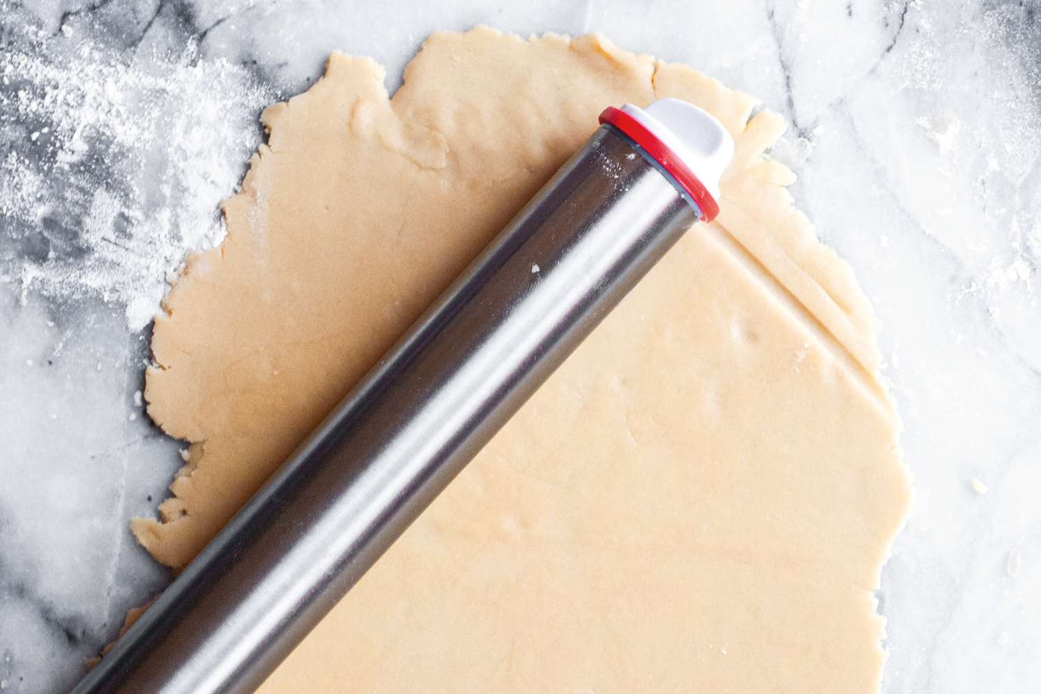 Rolling pin on rolledout pastry dough on a marble surface