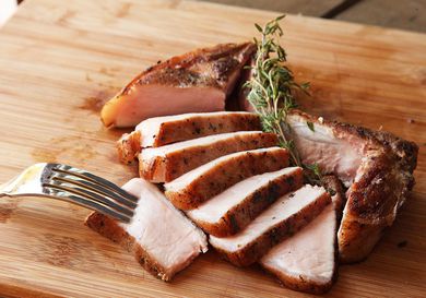 Sous vide bone-in pork chop, sliced, on a cutting board.