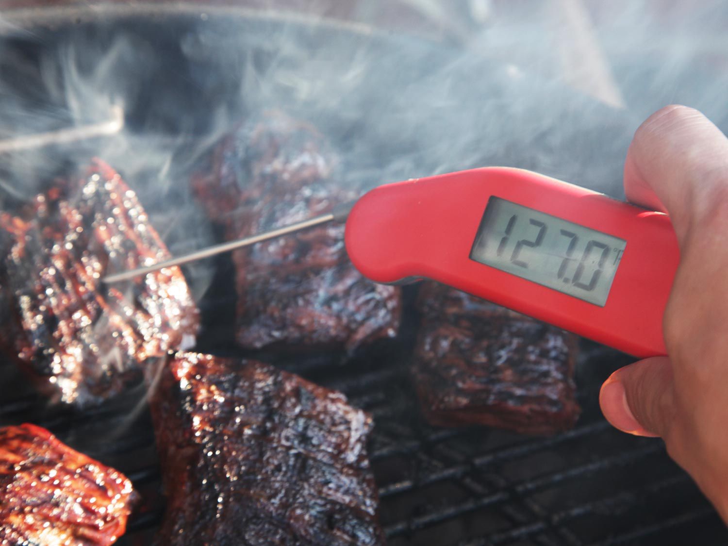 Using a probe thermometer to take the temp of steaks. Here it reads 127 degrees Fahrenheit.