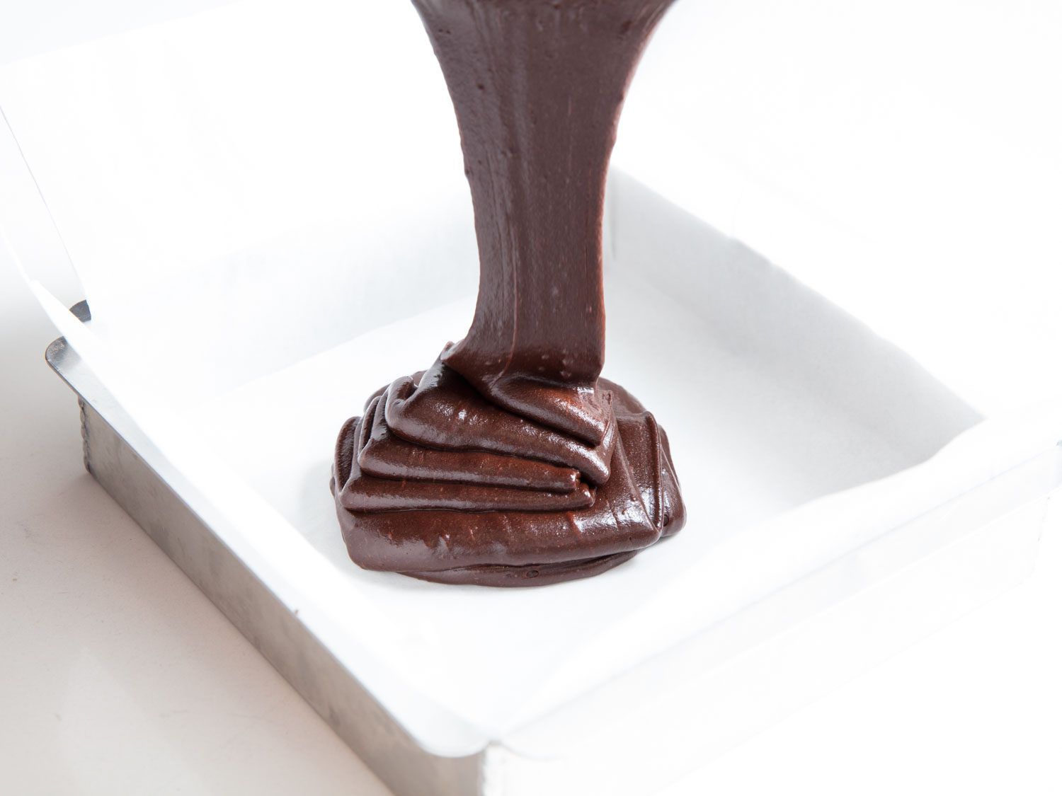pouring brownie batter into a pan
