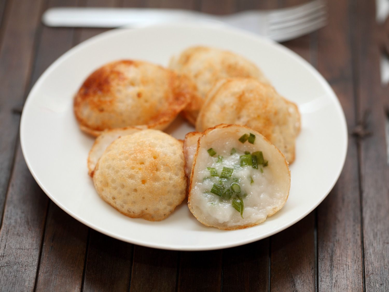 A white plate of serabi, small Indonesian pancakes made of rice flour and coconut.