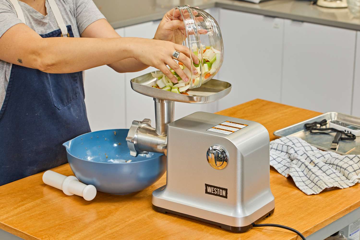 Person pouring bowl of chopped veggies to food tray of Weston #12 Electric Meat Grinder & Sausage Stuffer