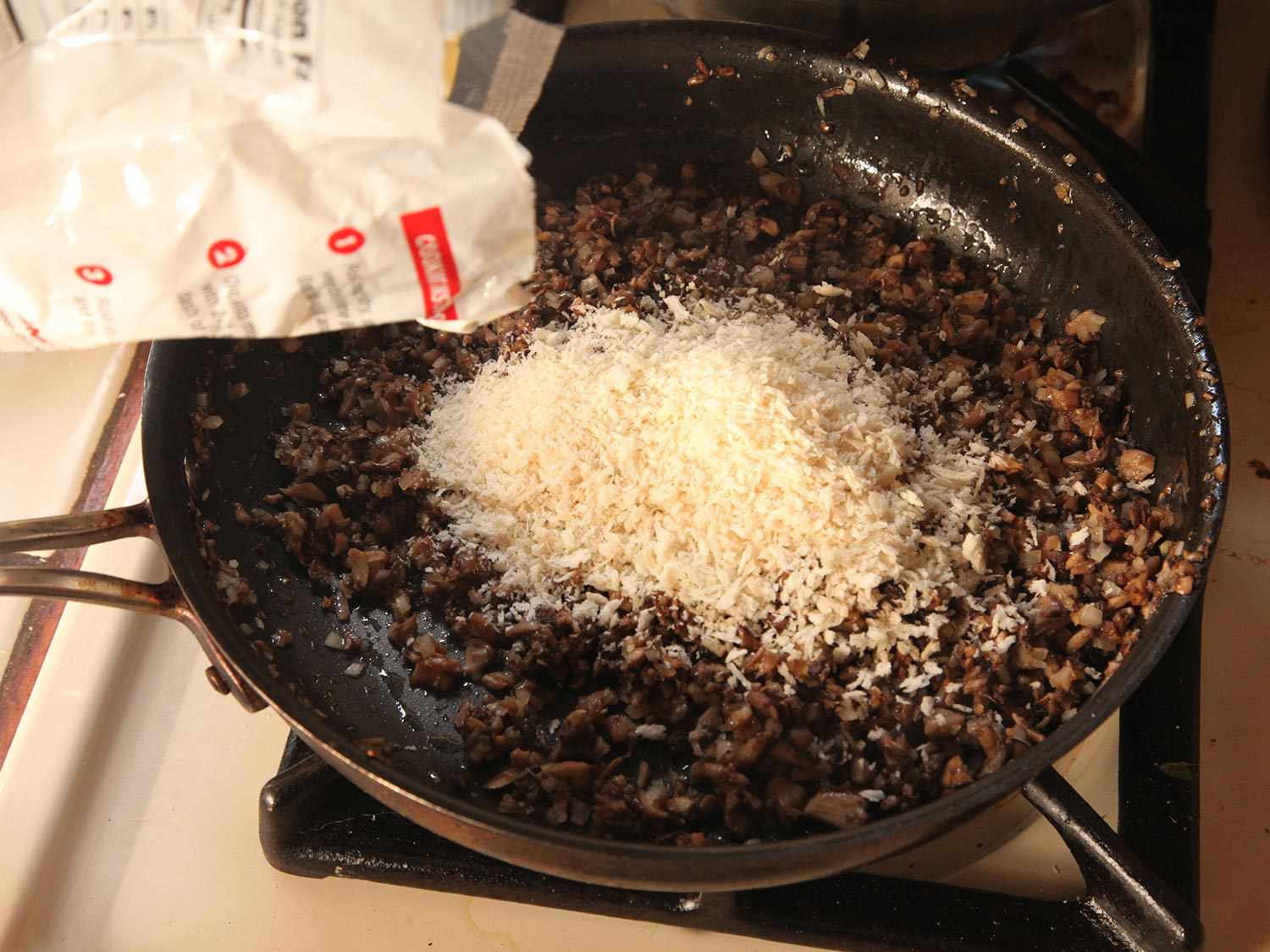 Adding panko to duxelles in skillet.