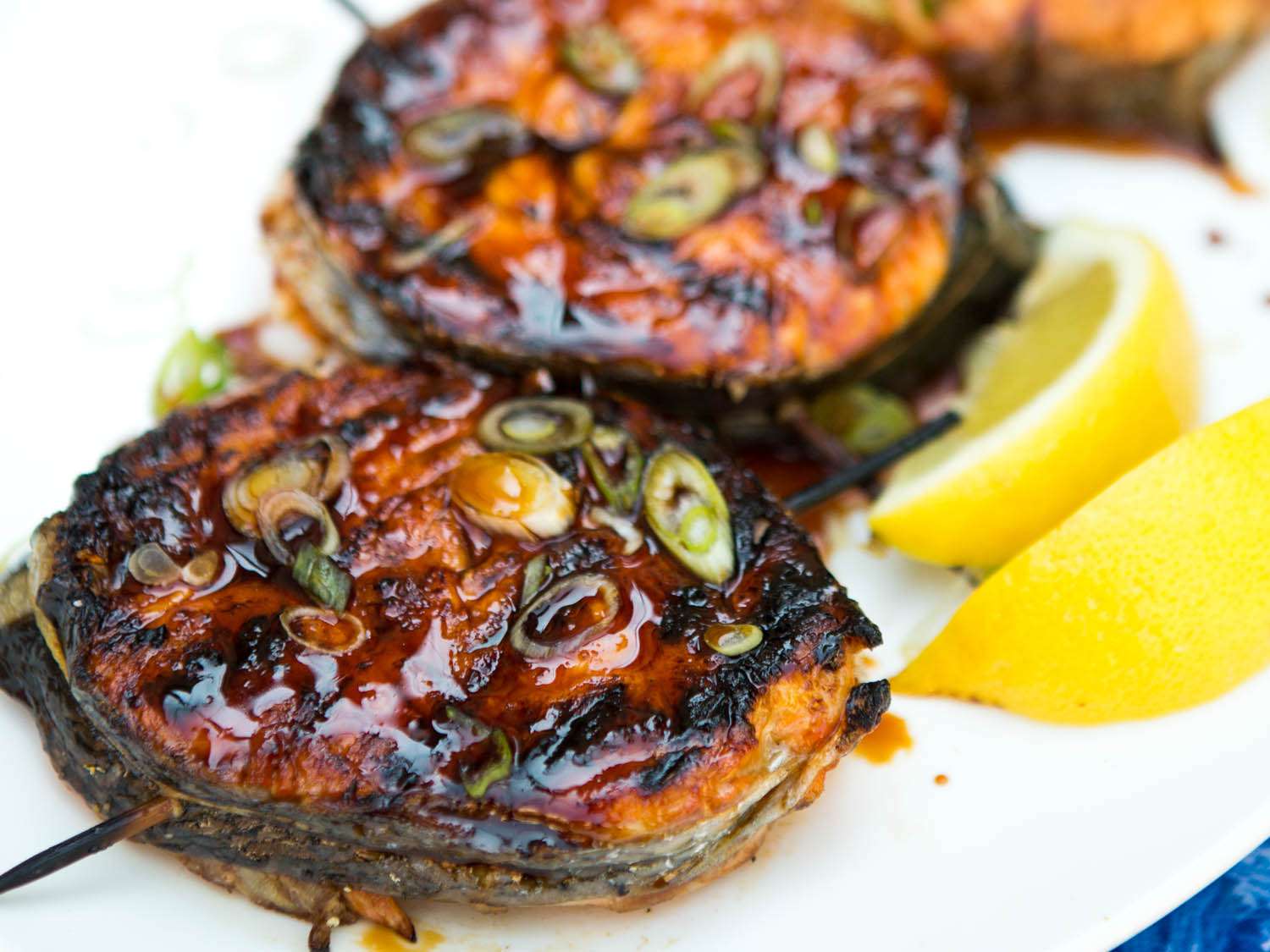 Grilled salmon steak medallions with sliced scallions, teriyaki sauce and lemon wedges.