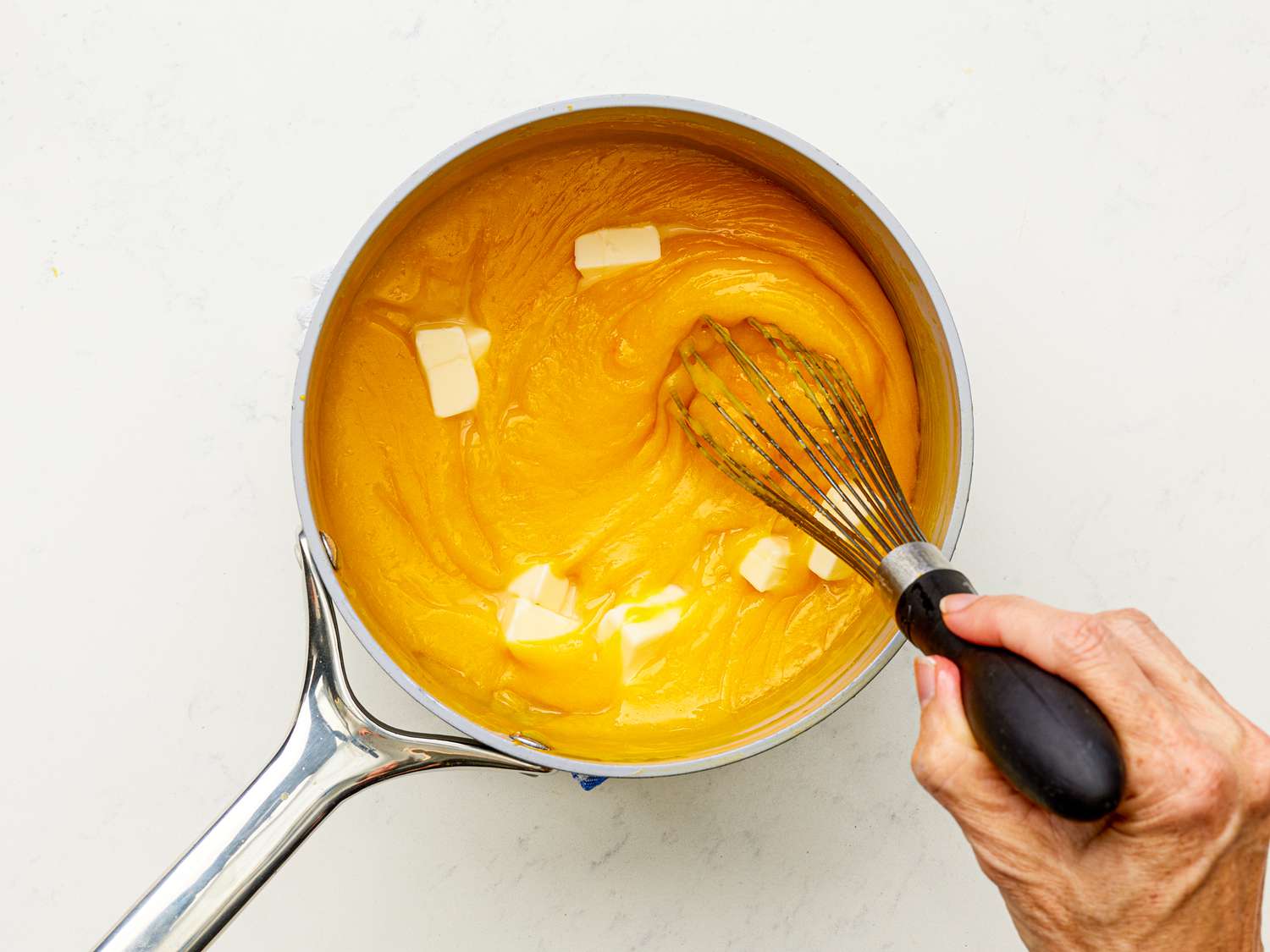 Overhead view of whisking butter into orange mixture