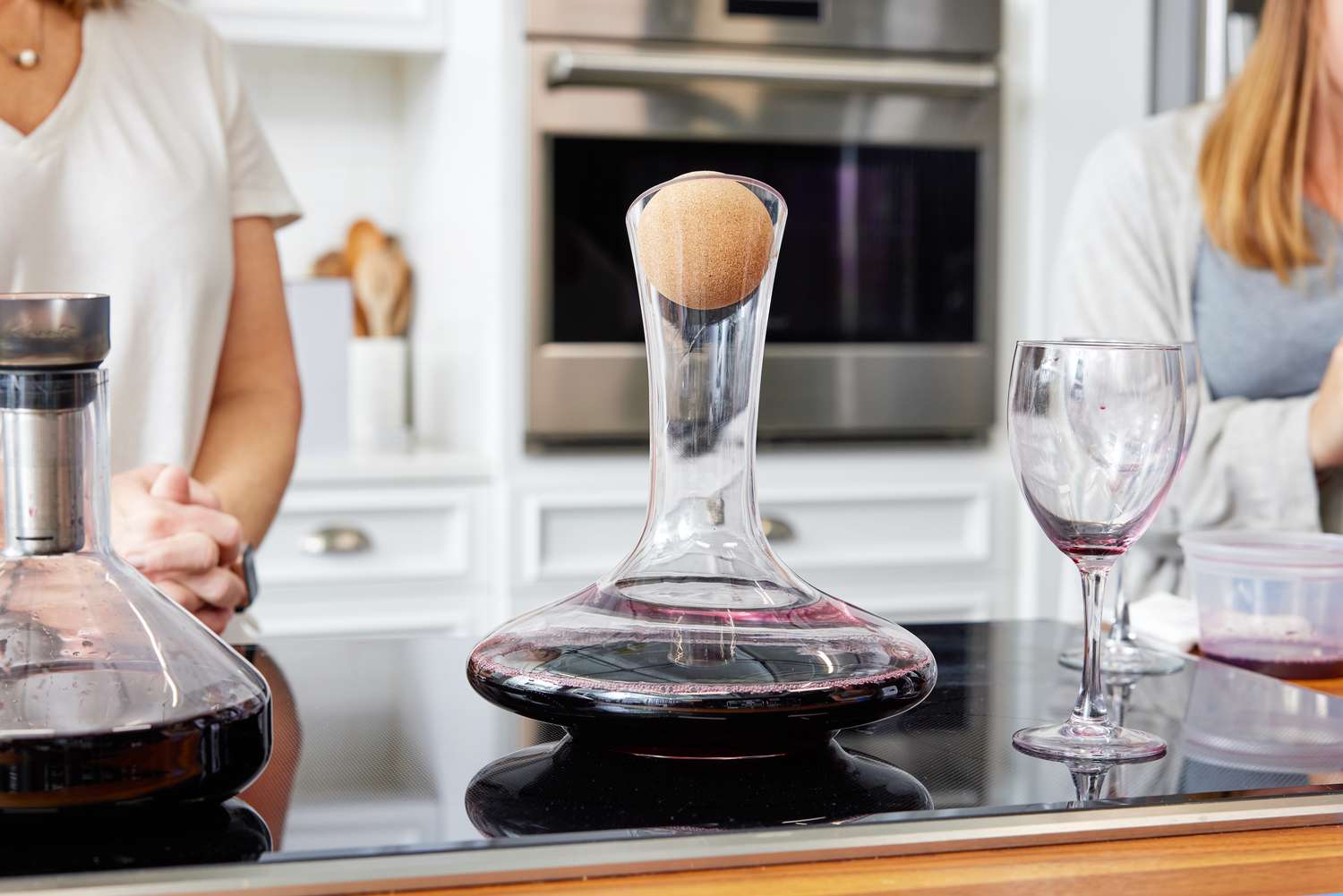 Two standard wine decanters in a kitchen with a wine glass beside them