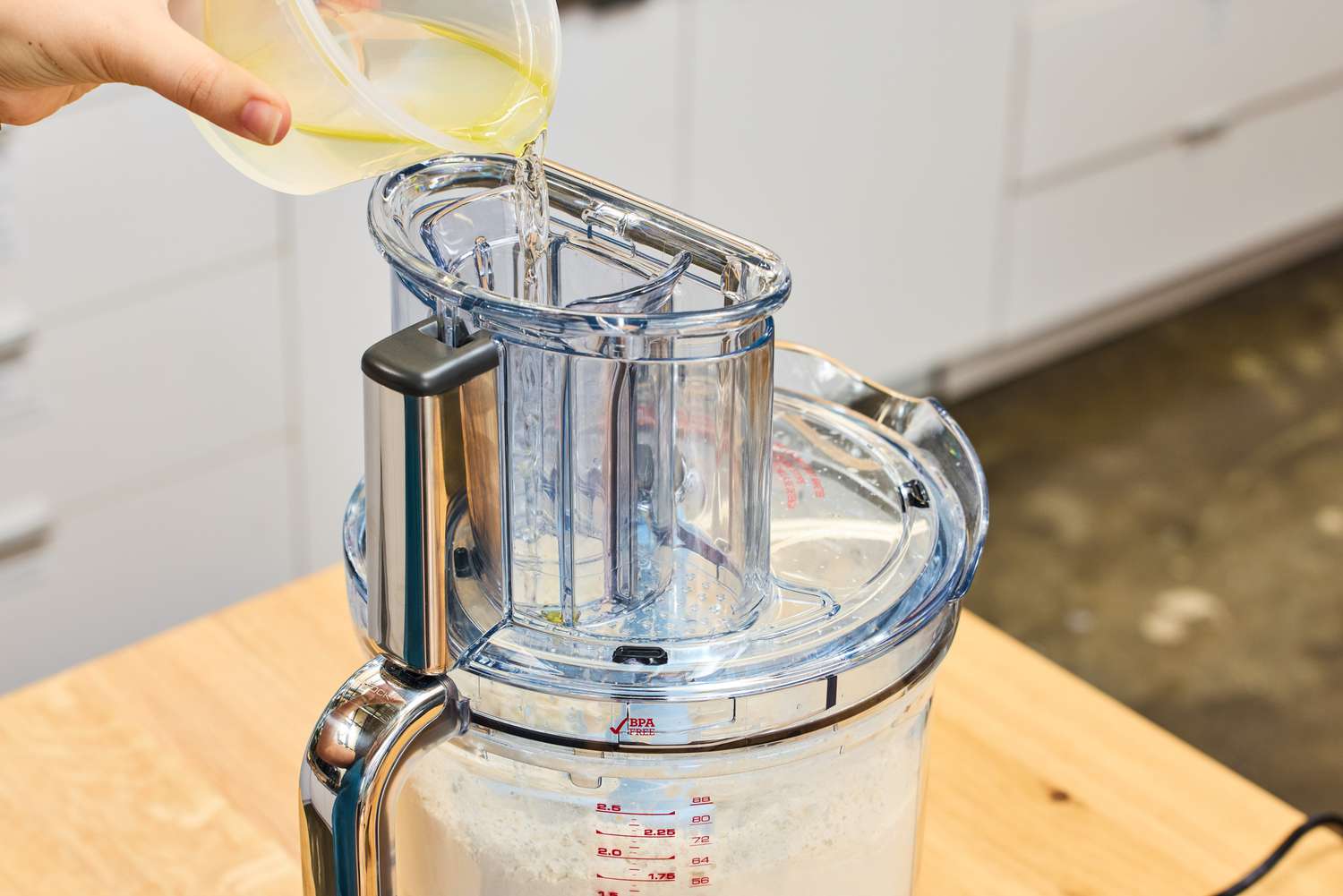 A person pours liquid into the Breville BFP838BSS1BNA1 16-Cup Paradice Food Processor