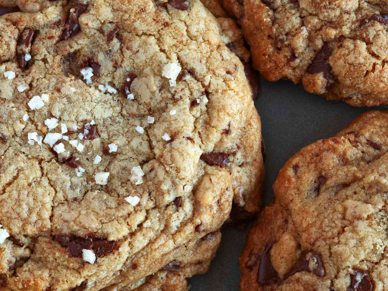 Extra-close-up chocolate chip cookies showing craggy top and salt flakes.