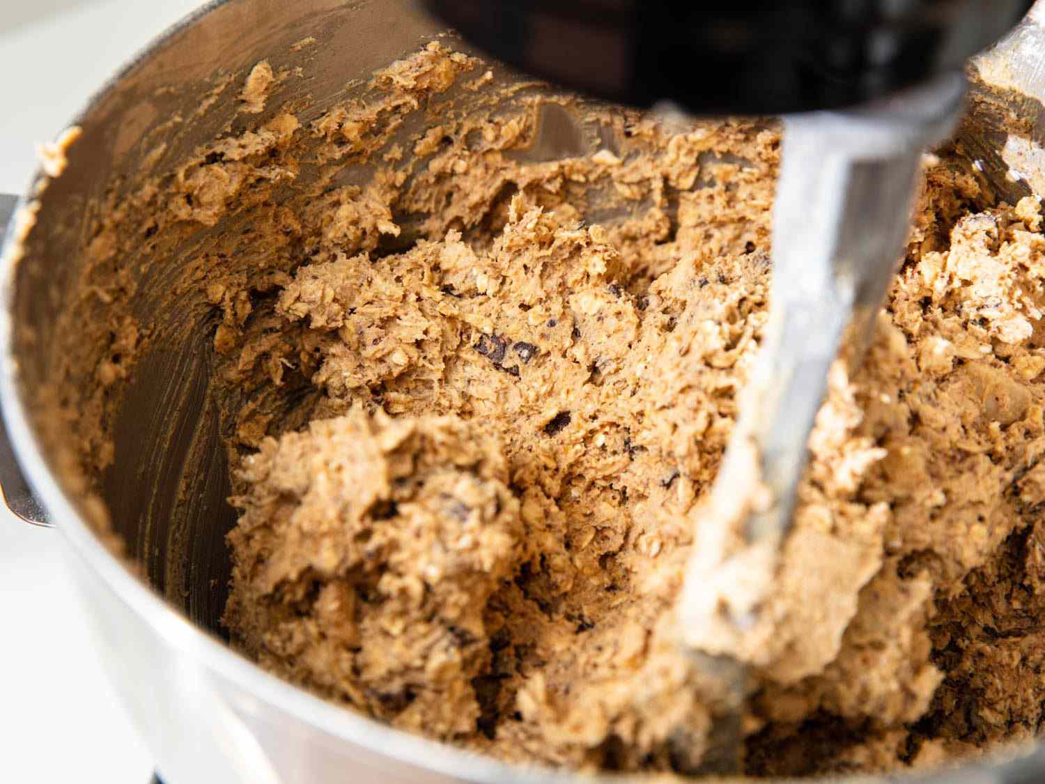 A stand mixer bowl filled with chunky, but well homogenized cookie dough.