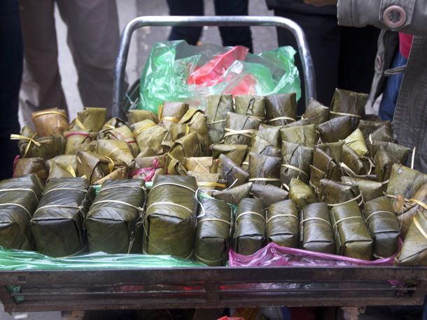 Dozens of banana leaf-wrapped banh chung sitting in a large basket 