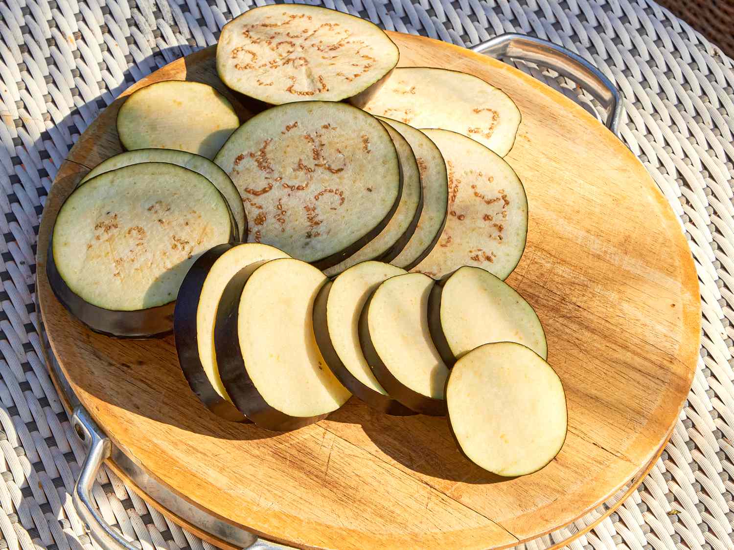 Sliced eggplant on a wooden platter outdoors