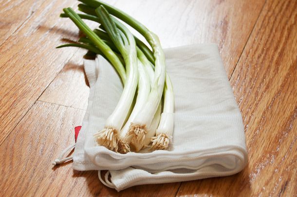 A group of five scallions resting on a white kitchen towel. 
