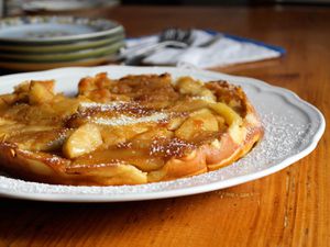 A German pancake with caramelized apples on a white plate