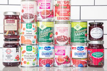 An assortment of canned and jarred cranberry sauces displayed on a counter in a tiled background setting