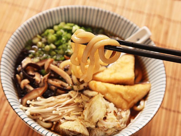Chopstick lifting noodles out of a bowl of vegan udon 