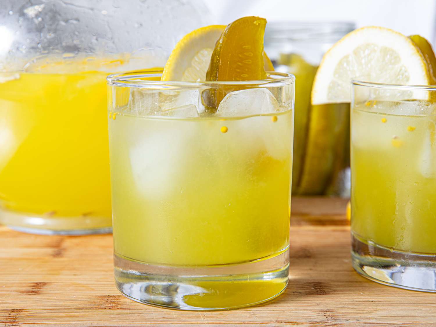 Glasses of pickle lemonade with lemon and pickle garnish