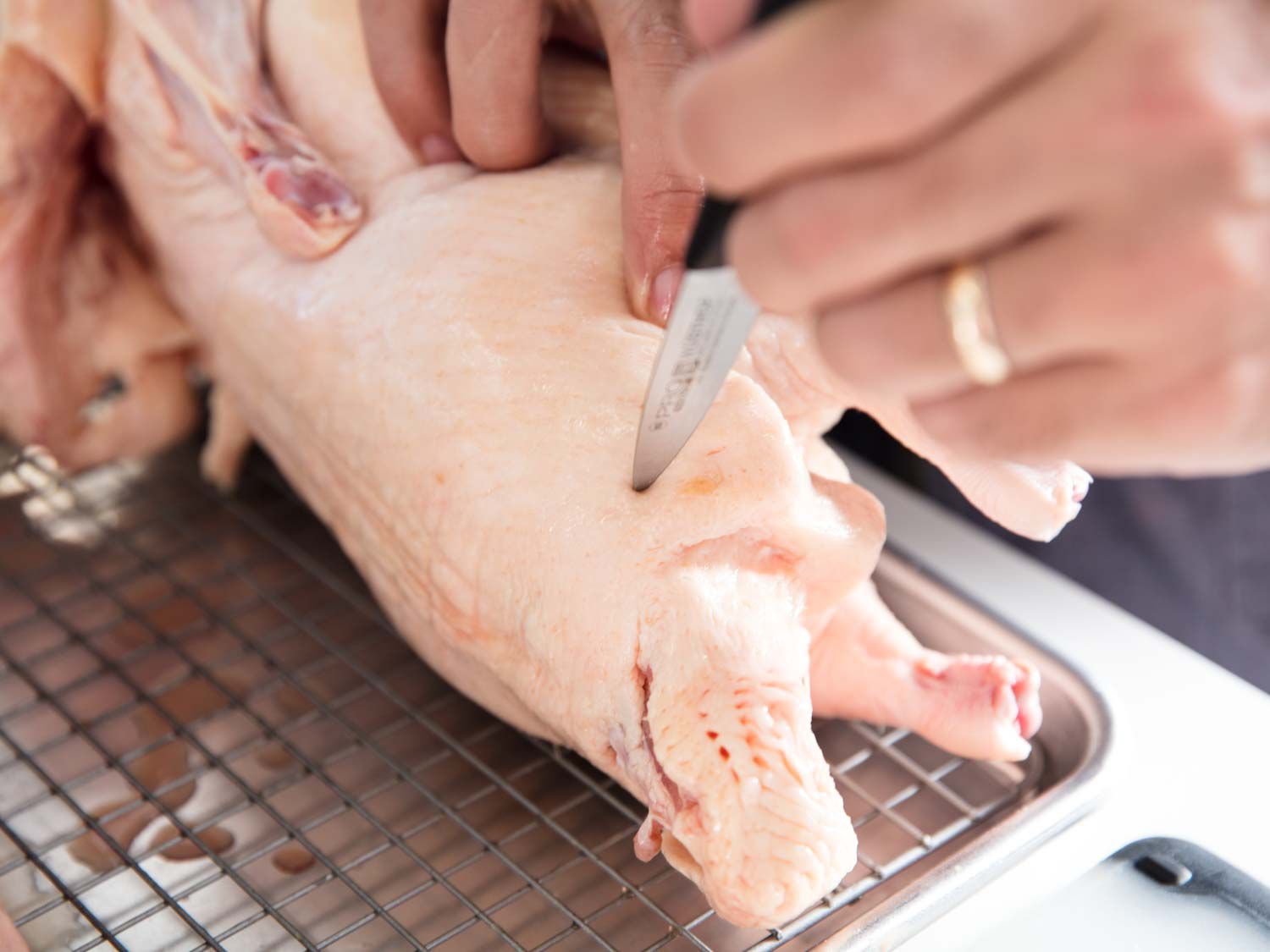 Scoring a raw duck with a paring knife