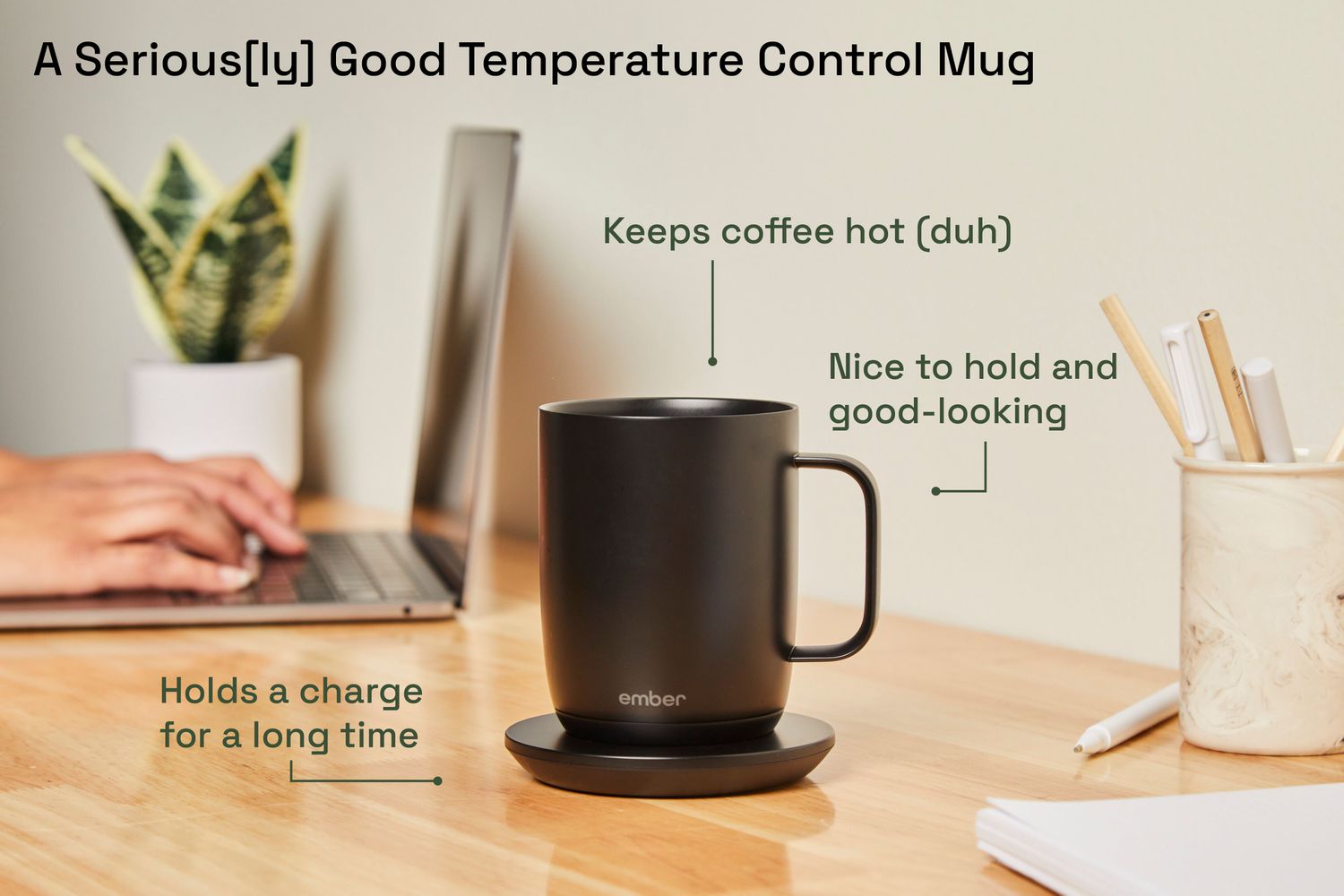The Ember temperature control mug on a charging pad in front of a laptop