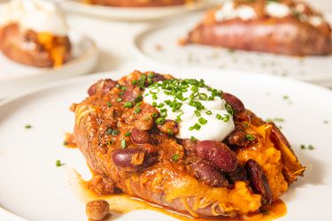 Side view of loaded backed sweet potato topped with cheese and beans 