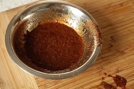 Peruvian grilled chicken marinade in a small metal bowl on a wooden cutting board.