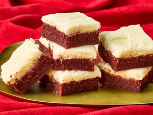 red velvet brownie squares stacked together on a gold platter on top of a red velvet backdrop