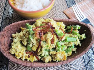 Balinese chicken lawar served in a wooden bowl beside a bowl of white rice