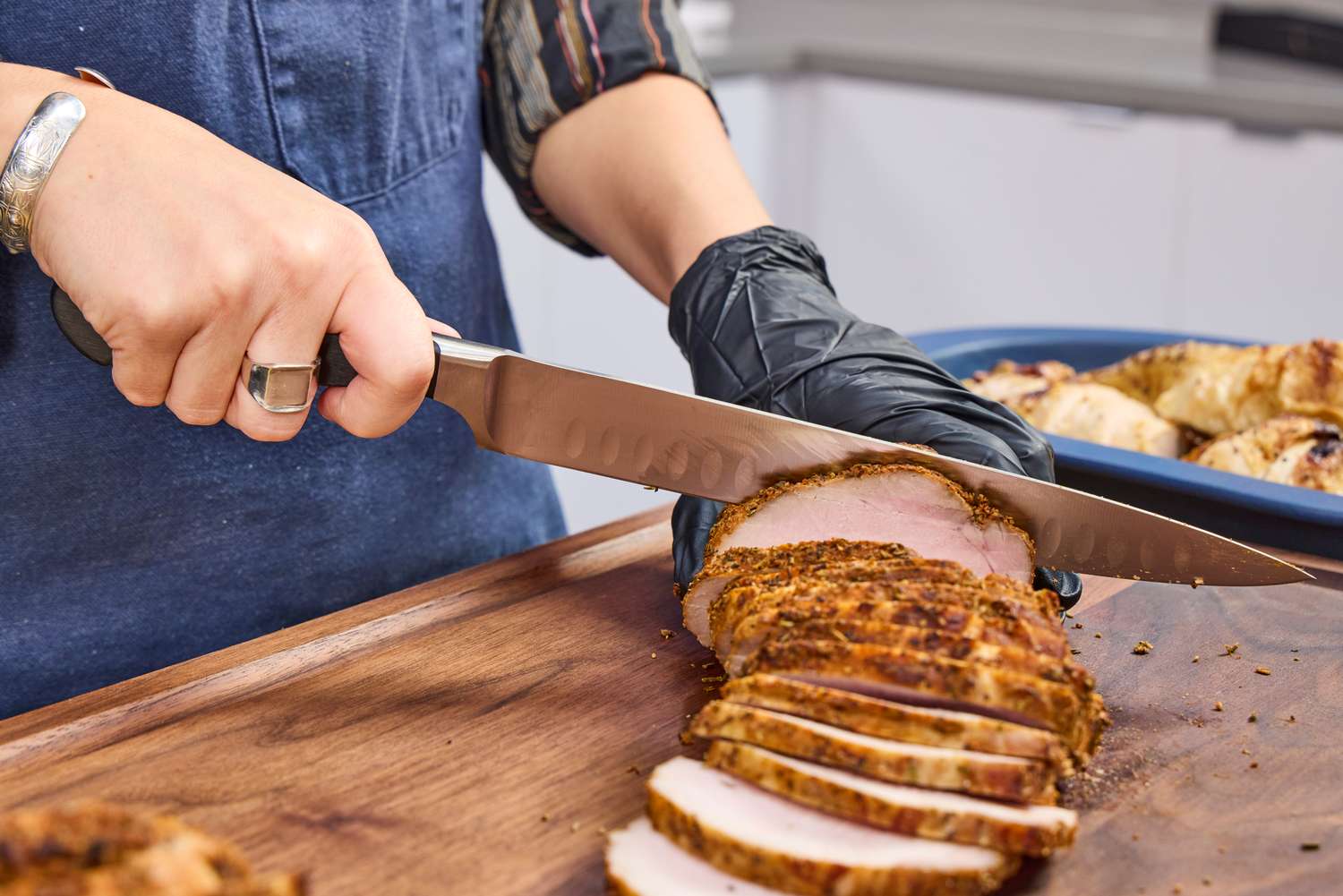 A person slices meat with the Wüsthof Classic 9 Inch Hollow Edge Carving Knife