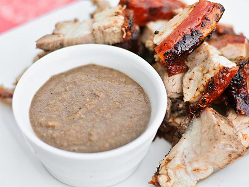A bowl of Filipino pork liver sauce next to pieces of lechon on a plate.