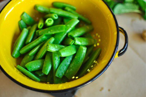 Trimmed and washed sugar snap peas in a yellow colander
