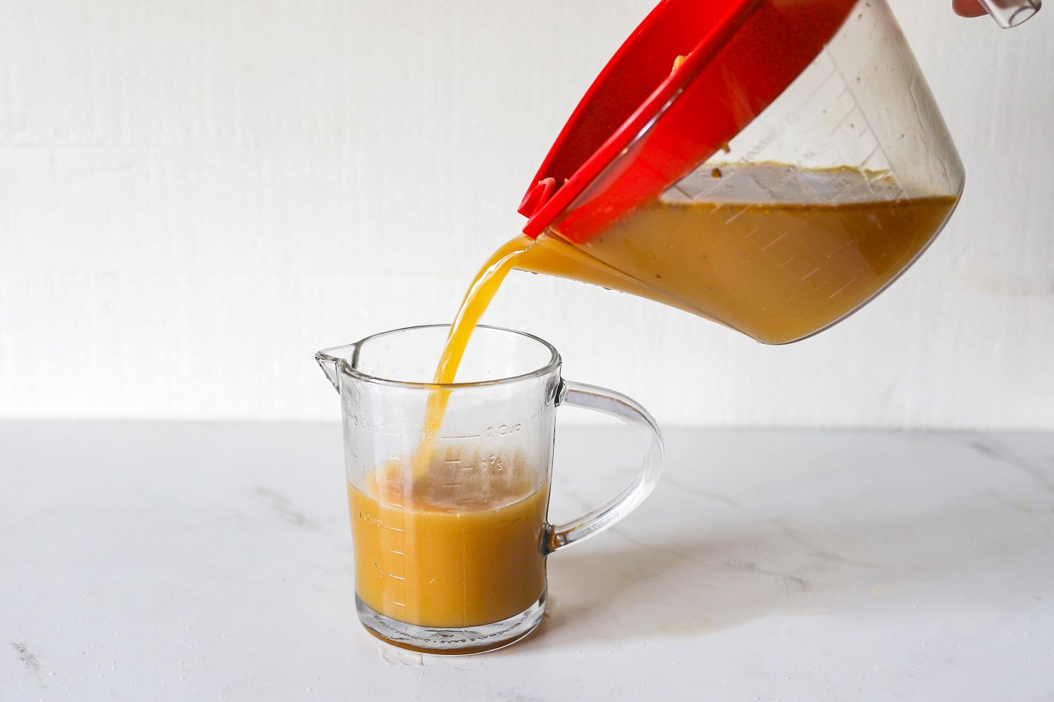 Stock being poured out of a fat separator into a measuring cup