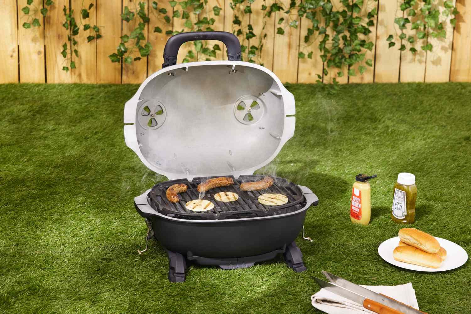 The PK grills portable charcoal grill cooking sausages.