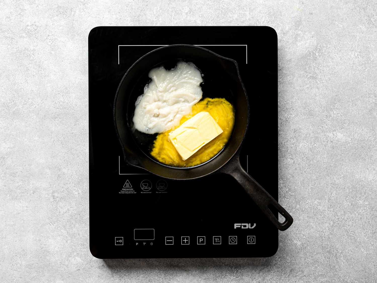 Dough ingredients, including lard, butter, and wet mixture, in a cast iron skillet on an induction cooktop.