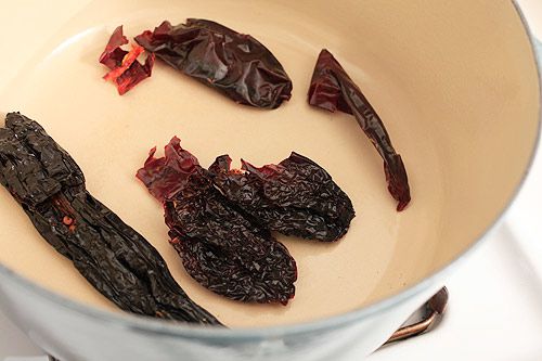 A mix of dried chiles in a Dutch oven