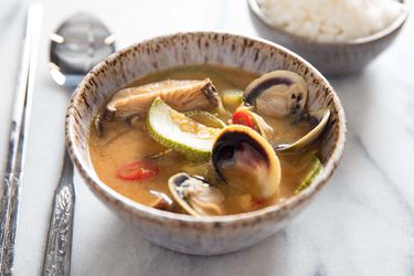 A bowl of doenjang jiggae full of mushrooms, squash, clams, and more.