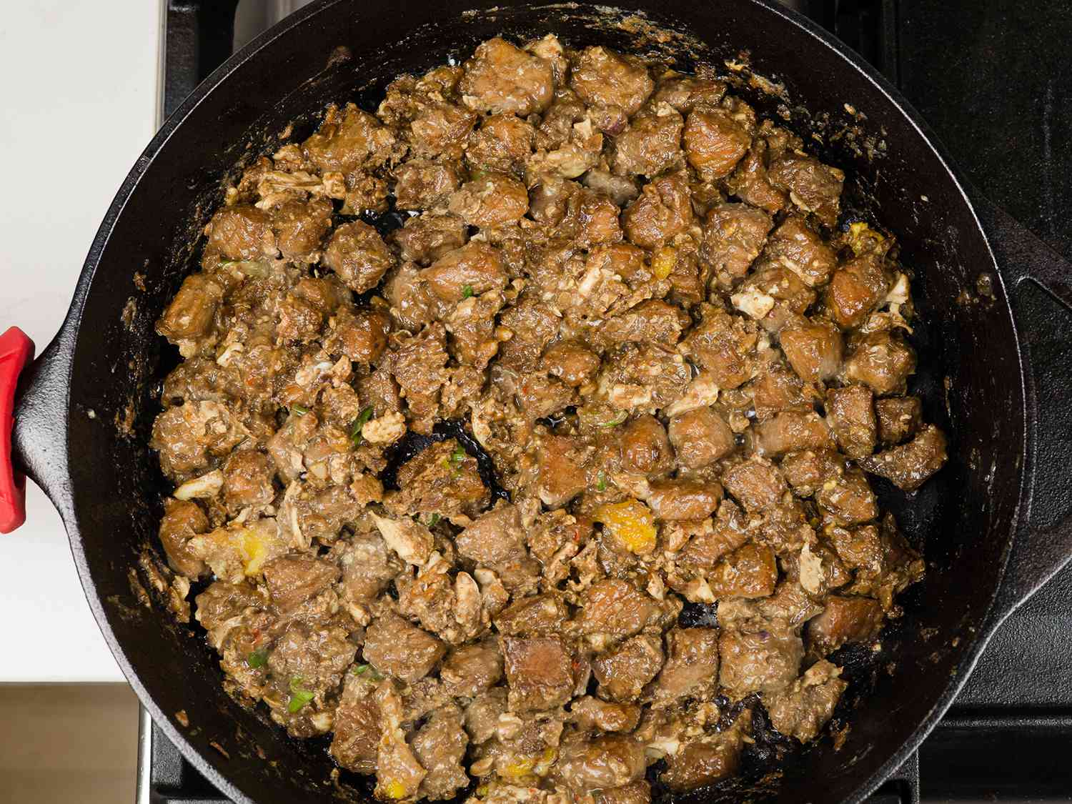 Mayonnaise and scallions mixed into the finished sissig, in a cast iron pan.