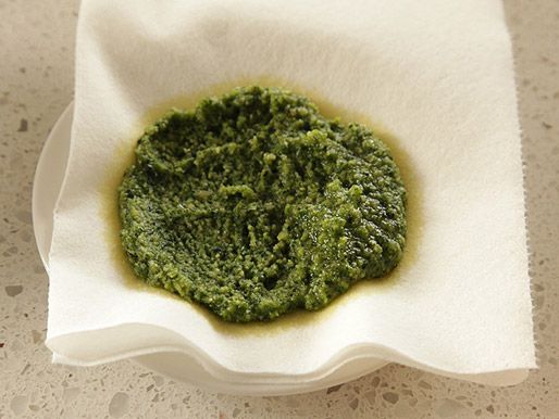 Pesto has been spooned onto a paper towel-lined plate to absorb excess oil.