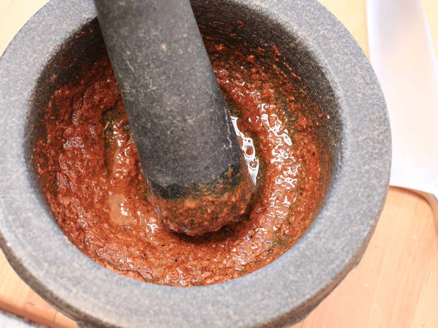 A mortar pounding in a pestle containing marinade for the Peruvian grilled chicken.