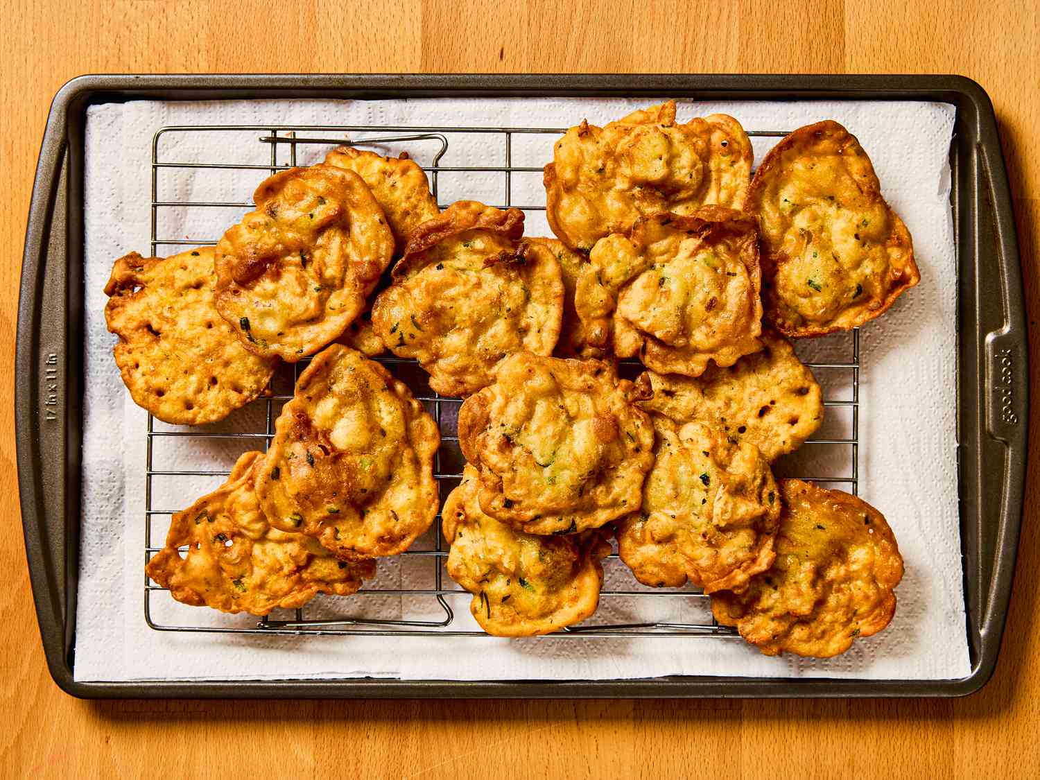 Bacalaitos on a cooling rack on a paper towel lined sheetpan 