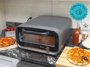 Compact pizza oven on a kitchen counter with freshly baked pizzas nearby