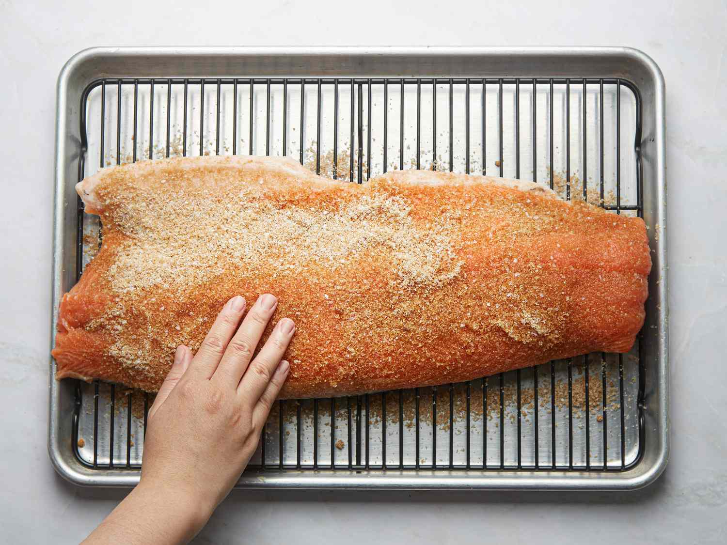 Overhead view of pressing salt into fish