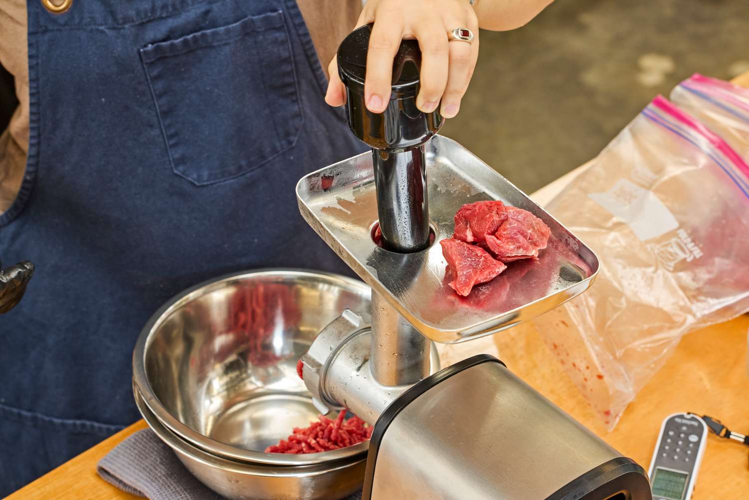 A person places cuts of meat into the Cuisinart Electric Meat Grinder