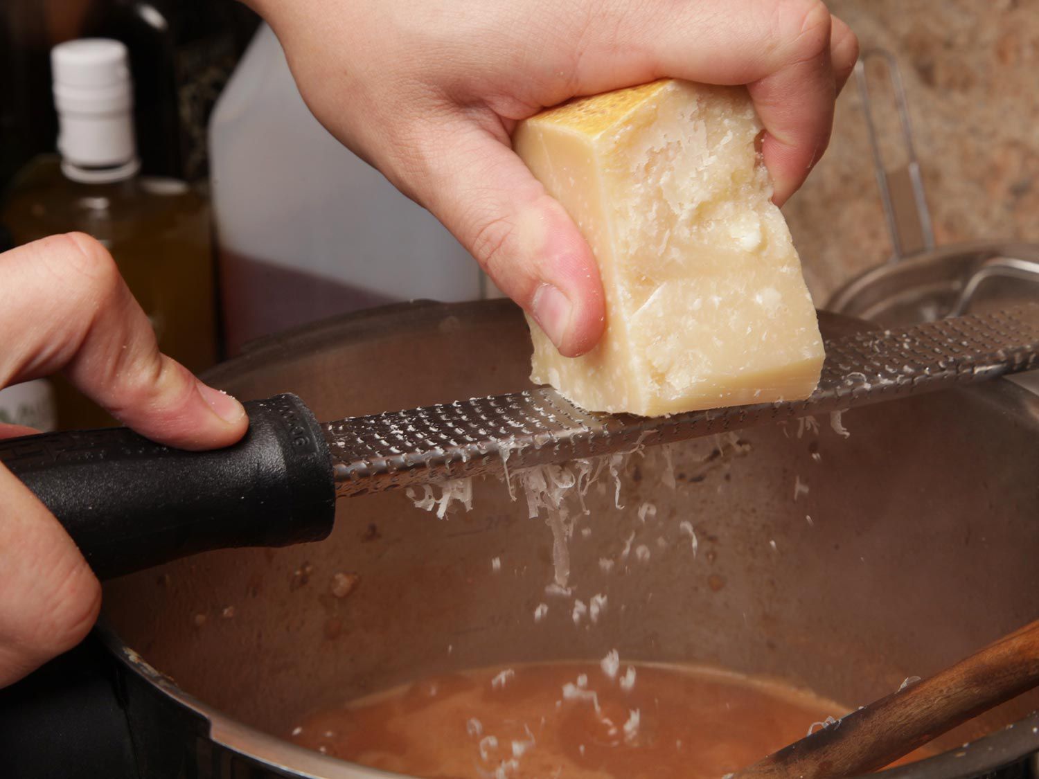 Author grating Parmesan cheese into the ragù Bolognese with a microplane.