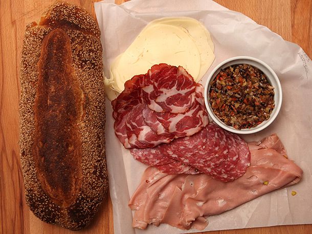crusty loaf of bread, thinly sliced mortadella, sweet sopressata, hot capicola, sharp provolone, and ramekin of olive salad 