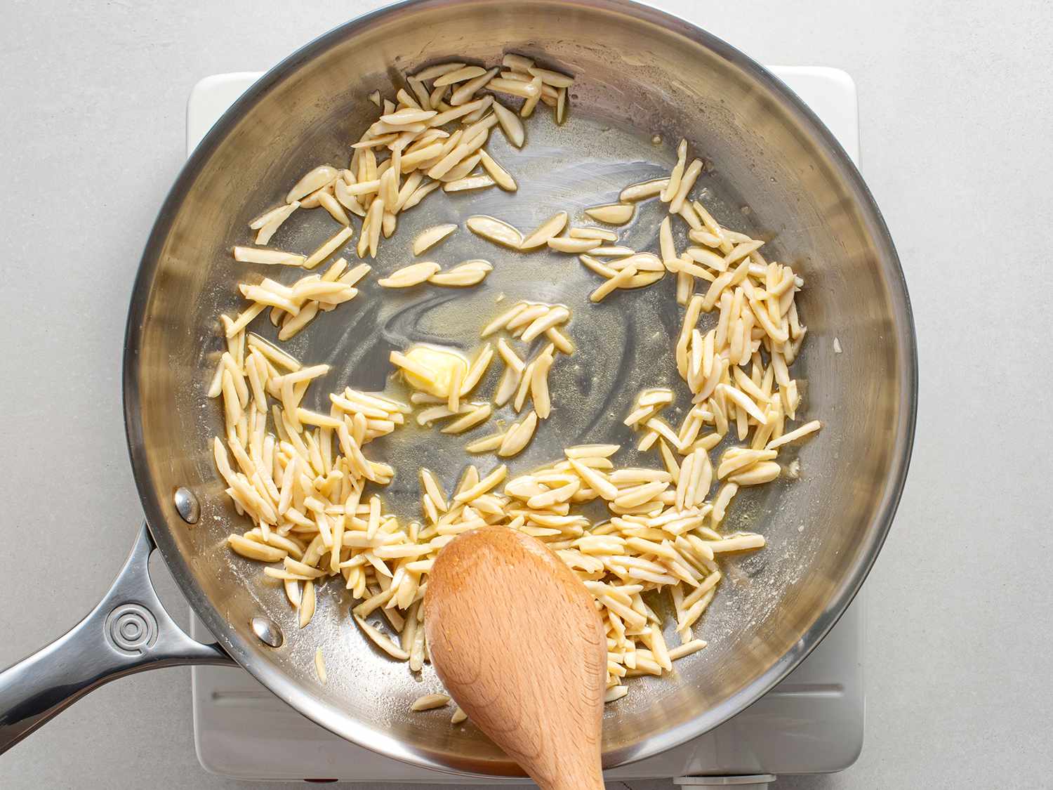 Slivered almonds being toasted in fat.